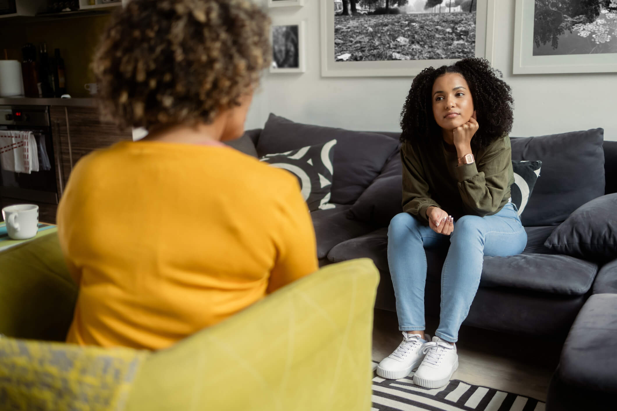 A young woman sitting on a couch across from a therapist listening intently.