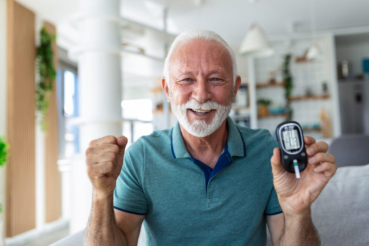 Senior man checking blood sugar level by glucometer and test stripe at home