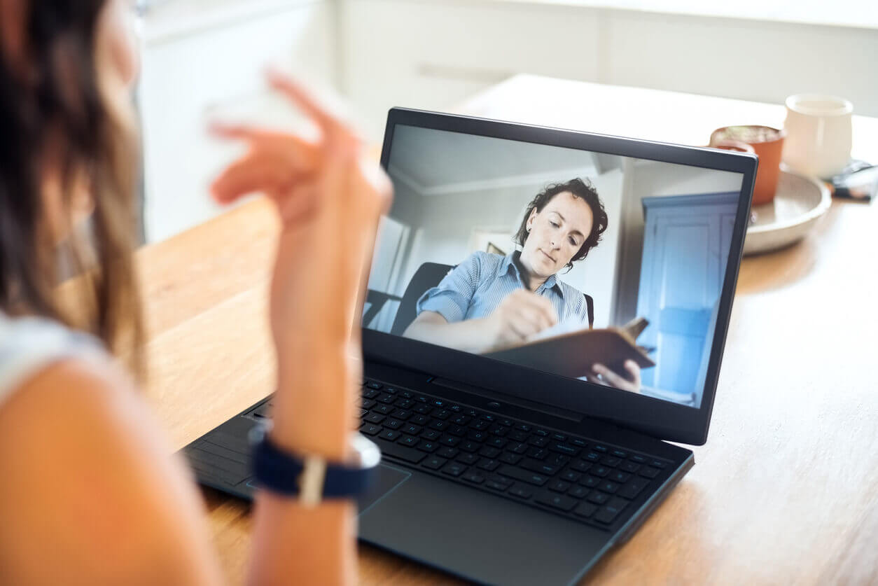 psychiatrist making notes during online session with patient