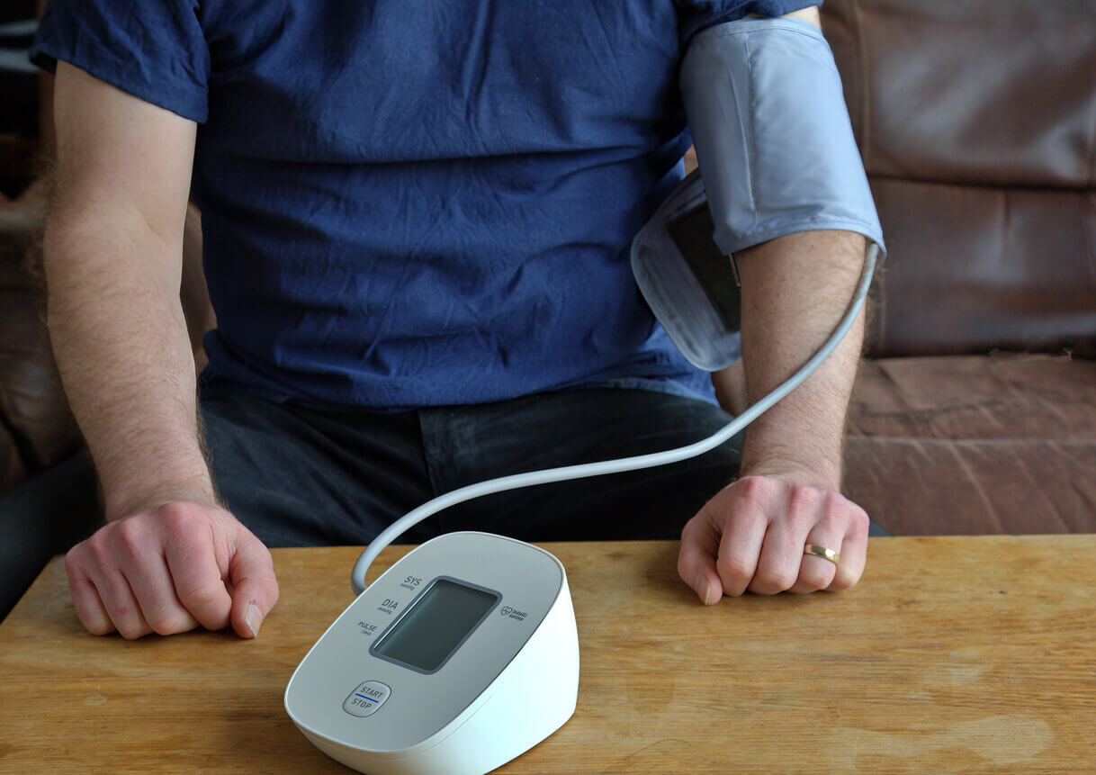 A man measuring his blood pressure at home.