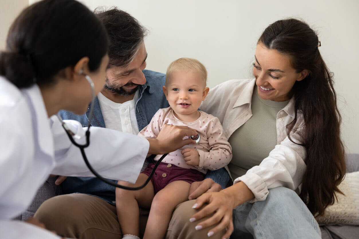 A female primary care doctor visiting a couple with their toddler for holistic family medicine care.