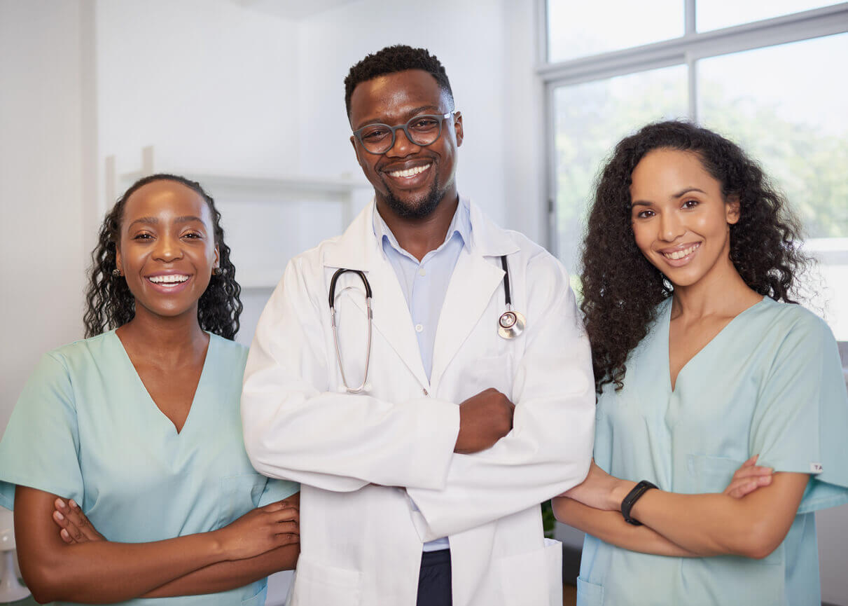 Three primary care providers stand in a row, smiling with their arms folded.