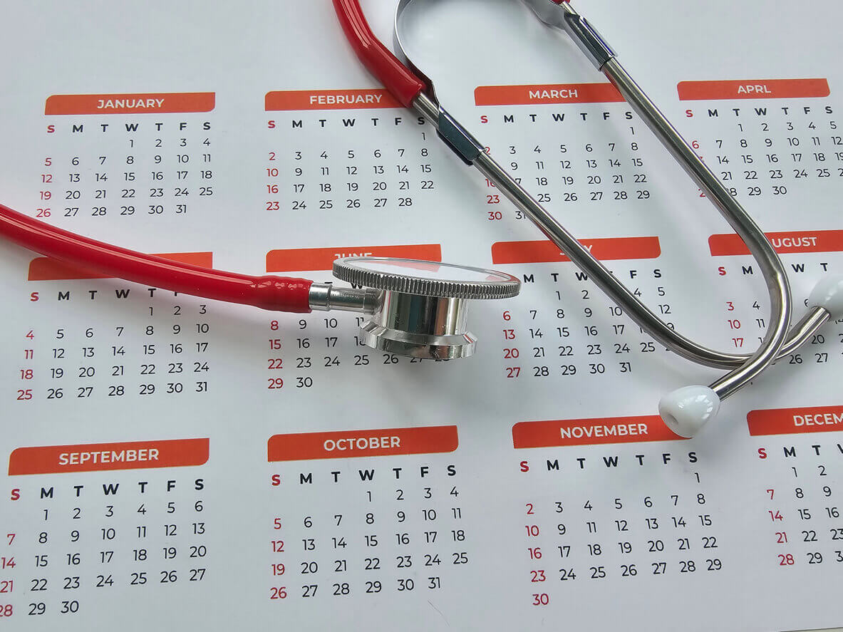 Stethoscope resting on a calendar with marked dates indicating health appointments for annual checkup.